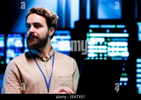 IT Specialist looking at operational servers in computer network security data center. Mainframes providing processing and memory resources needed for computational operations Stock Photo