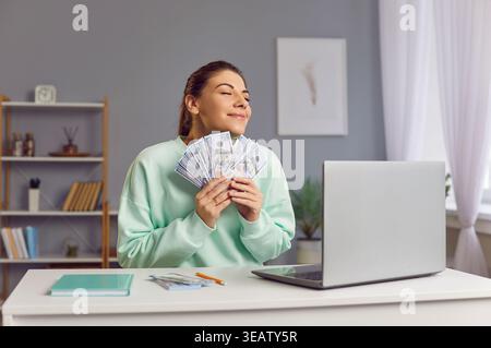 Happy Woman Holding Stack Of Cash And Celebrating Financial Success Stock Photo