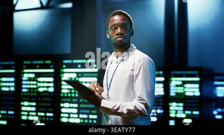 Computer scientist using tablet to check server room security features protecting against unauthorized access, data breaches, distributed denial of service attacks and other cybersecurity threats Stock Photo
