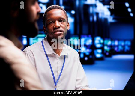 Teamworking computer scientists dealing with server cluster system failures. Servicemen brainstorming ideas on how to best minimize cloud computing business downtime and prevent crashes Stock Photo