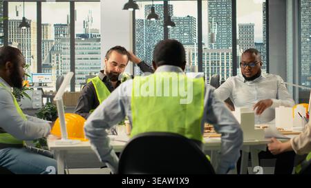 Real estate developers and architects in a modern office reviewing blueprints and 3D models. Diverse development team discusses urban planning and property investment strategies. Stock Photo