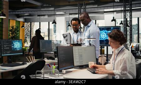 Programmers in office doing software development to launch new features, brainstorming ideas. Teamworking colleagues in startup company writing computer programs, camera A Stock Photo