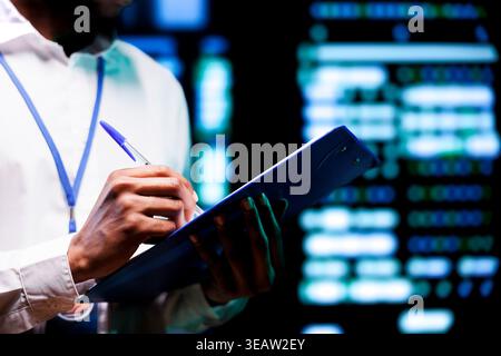 Serviceman carries out precise storage devices diagnostic test, writing components in need of servicing. Expert ensuring seamless operation of server hub and data center equipment Stock Photo