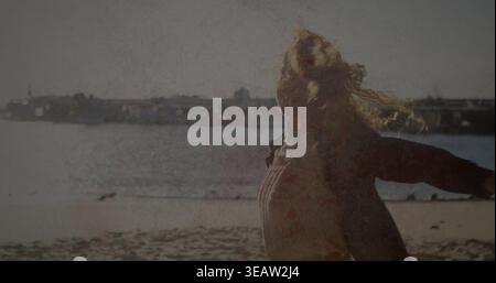 Standing woman with windblown hair wearing dark coat and lighter top on sandy beach, copy space Stock Photo