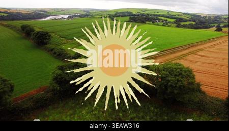 Displaying large stylized sun graphic covering rolling green pasture and golden field on farm Stock Photo