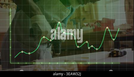 Drilling man using drill at workshop, wearing gloves, longsleeve shirt, board, tape, chart overlay Stock Photo