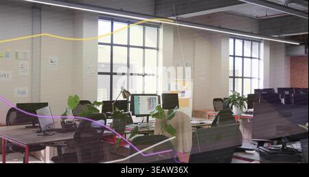 Showing central workstations featuring multiple monitors, chairs and plants in open-plan office Stock Photo