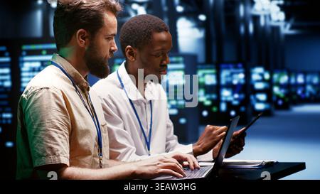 System administrators running analysis on servers helping businesses manage databases, host websites and store files. Technicians auditing data center equipment used for high performance computing Stock Photo