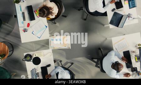 Top down view of professional employees working together in office. Diverse work team collaborates on project planning, analytics and report writing for corporate development. Stock Photo
