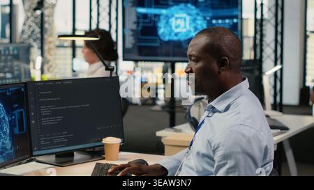 Data scientist in office automating workflows using artificial intelligence on PC. IT professional refines deep learning computational models on computer for faster processing, camera B Stock Photo