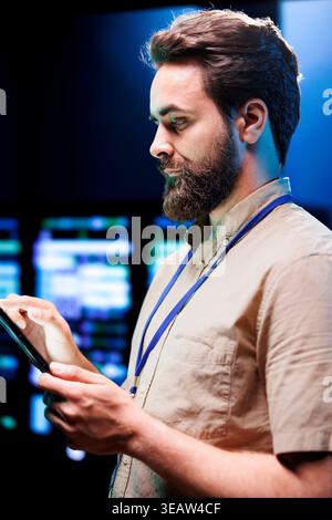 Cloud computing business executive imputing audit data in server room supporting AI through high performance computing. Skillful expert making sure supercomputers are operating flawlessly Stock Photo
