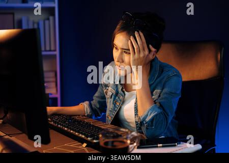 Stressful young beautiful asian creative looking on pc to search project creator social media online with planning channel strategy reach of more Stock Photo