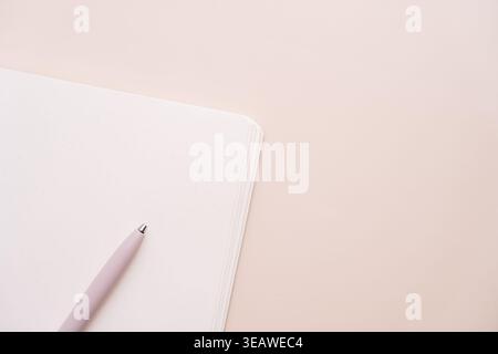 Pink pen and notebook on beige background with copy space Stock Photo