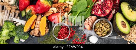 Fresh vegetables, grains, leaves and fruits on a dark background. Vegan food concept. Top view. Stock Photo