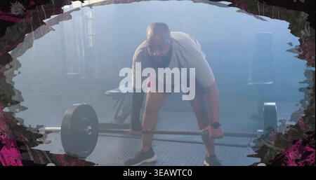 Bending bearded man gripping loaded barbell on gym floor, wearing red shorts watch elbow sleeve Stock Photo