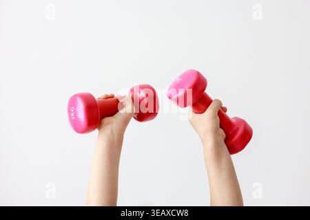 Child's Hands Lifting Two Pink Dumbbells Up Stock Photo