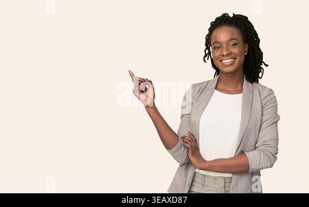 Woman Points to the Side While Standing in a Studio Against a Plain Background Stock Photo