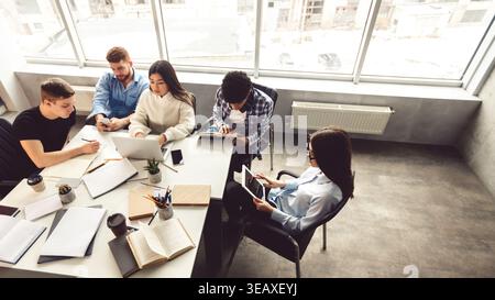 Collaborative Group Working on Laptops and Notebooks in Modern Office Space During Daytime Stock Photo