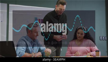 Explaining man in black shirt leaning and holding pen at office, with laptop, papers, waveform Stock Photo