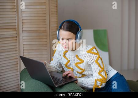 Teen girl browsing internet and listening music on laptop at home Stock Photo