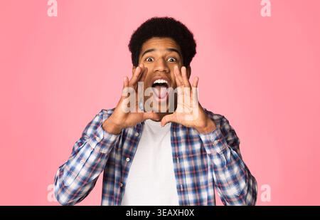 Attention. Guy shouting, holding hands near mouth Stock Photo
