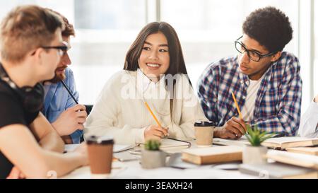 Happy multiracial college students studying with books in library Stock Photo