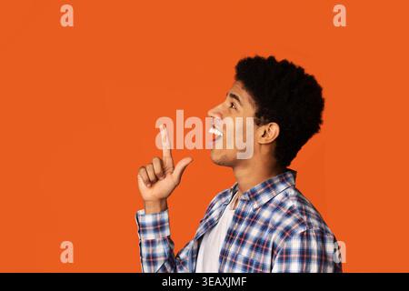 Young Man Expressing Excitement Against a Vibrant Orange Background Stock Photo