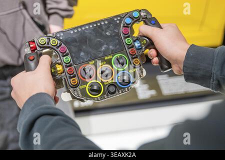 Close-up of a Formula 1 steering wheel with many buttons and functions held by two hands, Porsche Museum, Stuttgart, Germany Stock Photo