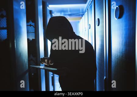 Criminal, hacking and tablet in data center at night for malware, cyberattack and ransomware. Hacker, person and coding virus with digital for Stock Photo