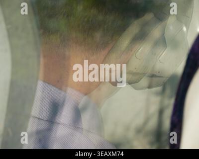 Train passenger wearing headphones reflection in train carriage window. UK Stock Photo