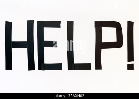 The "Help!" sign was created with black electrical tape on a white background. Stock Photo