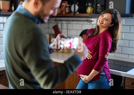Pregnant woman with her husband taking photos. Happy couple who can't wait to become parents Stock Photo