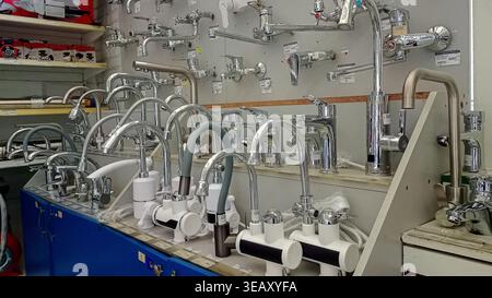 Various modern chrome and steel water faucets and kitchen taps on display at a plumbing hardware store. Stock Photo