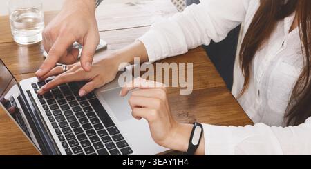 Hands Working Together on a Laptop at a Wooden Table in a Bright Indoor Space Stock Photo