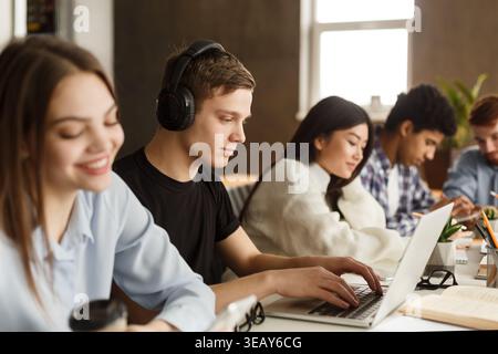 Students Engaged in Study Session at Modern Workspace With Technology and Coffee Stock Photo