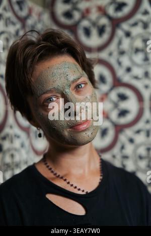 Portrait of woman with green clay face mask looking at camera, Bali Stock Photo
