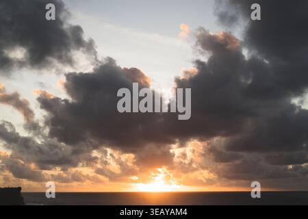 Dramatic sunset with sun breaking through dark storm clouds, Bali Stock Photo