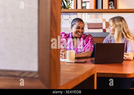 Two female coworkers smiling at an office meeting Stock Photo