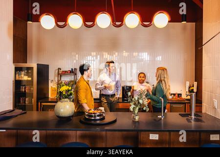 Young Office Team Having a Discussion In Kitchen Stock Photo