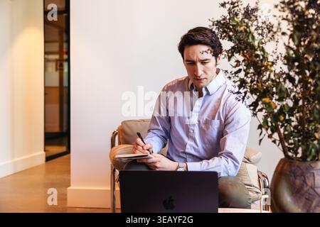 Caucasian man writing in notebook at work Stock Photo