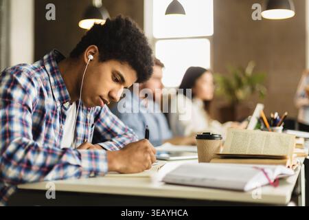 Black guy taking notes, preparing for classes in library Stock Photo