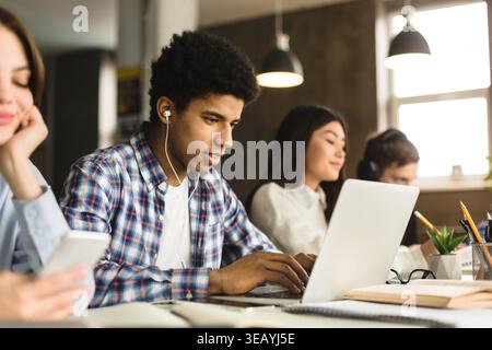 Students Engaged in Study Session While Using Technology in Modern Workspace Stock Photo