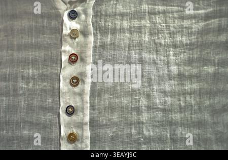 Close up of white linen shirt with colorful buttons, showcasing natural fabric texture and contemporary fashion design. Stock Photo