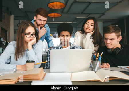 Smart serious students working on project in front of laptop Stock Photo