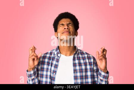 Guy crossed fingers and praying with eyes closed Stock Photo