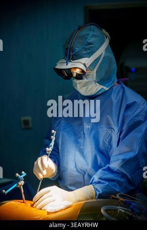 Surgeon performing robotic-assisted spine surgery using MediThinQ Scopeye smart glasses in an operating room Stock Photo