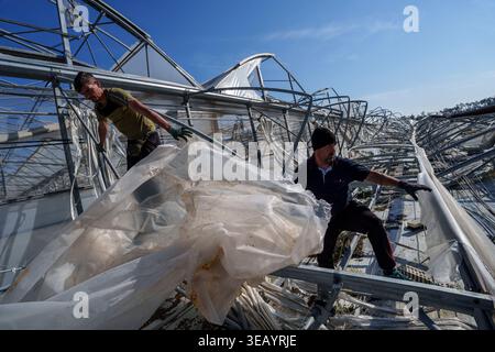 Emergency workers clear debris and damaged road infrastructure near a ...
