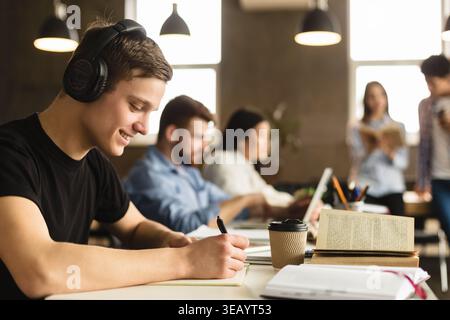 Student guy preparing for classes, taking notes in library Stock Photo