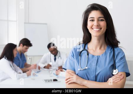 Happy Intern With Crossed Arms Looking At Camera During Conference Stock Photo