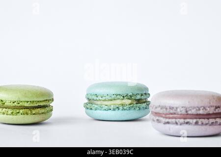 Three colorful French Macarons on gray background, cakes with different flavors, mint, apple, currant flavor. Homemade dessert, macaroons aquamarine, Stock Photo